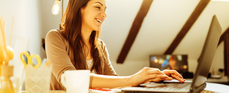 A girl smiling and looking at the laptop screen