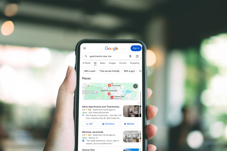 Hand holding a phone showing Google local results for apartments, including a map and listings
